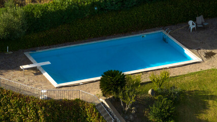 Empty swimming pool in a garden. There is a trampoline for diving.