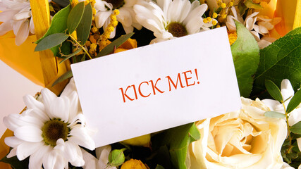 \Word KICK ME on a business card placed in a gift bouquet of flowers.
