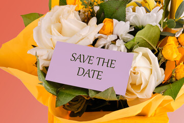 SAVE THE DATE concept on a purple business card in a bouquet of delicate roses