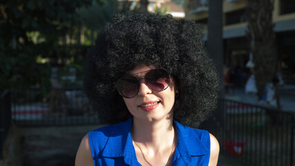 Portrait of a woman with curly hair bright sunlight wearing glasses.