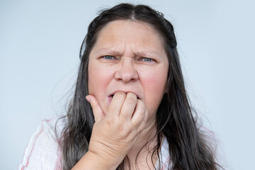 distressed mature woman with long hair nervously biting her nails, victim domestic violence...