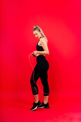 Blond woman with jump rope in studio, yellow red and dark background