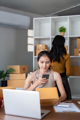 Entrepreneur managing online business from home office. ecommerce owner preparing packages for shipment and checking orders on a smartphone.