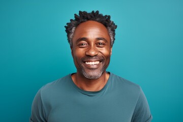 Fototapeta premium Portrait of a grinning afro-american man in his 40s smiling at the camera isolated in soft teal background