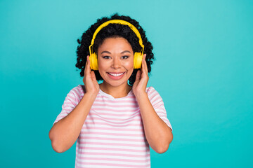 Photo portrait of funny youngster girl with curly hairstyle listen music her new wireless headphones isolated on cyan color background