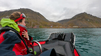 Traveler woman in an Arctic rib boat safari in Longyearbyen, Svalbard. Equiped tourist exploring...