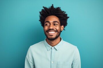 Obraz premium Portrait of a glad afro-american man in his 20s smiling at the camera on soft teal background