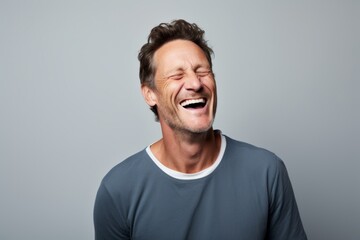 Portrait of a grinning man in his 40s laughing in soft gray background