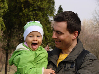Portrait of little adorable smiling girl and father in spring outdoors.