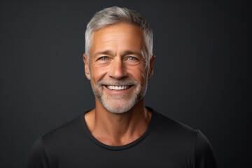 Obraz premium Portrait of a smiling man in his 50s smiling at the camera on soft gray background