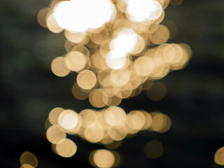 Abstract bokeh lights create a mesmerizing pattern of golden circles against a dark background, evoking a sense of warmth and tranquility.