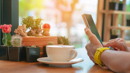 Business woman hands with smart phone and cup of coffee with beautiful cactus on table. Hands of...
