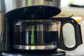 A black Coffee Maker with a hot coffee in the jug