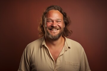 Portrait of a joyful man in his 40s smiling at the camera on soft brown background