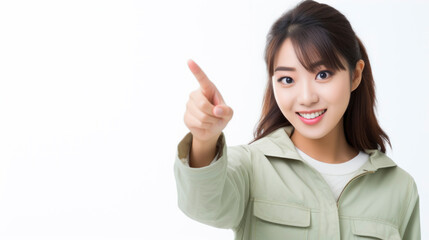 A young woman in a green jacket is pointing at something off-camera with a smile on her face.