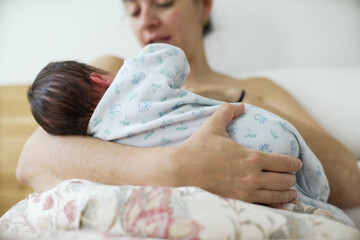 Mother gently holding her newborn baby in her arms, showcasing the nurturing love and intimate...