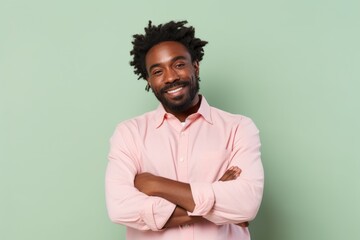 Obraz premium Portrait of a satisfied afro-american man in his 30s with arms crossed in front of pastel or soft colors background