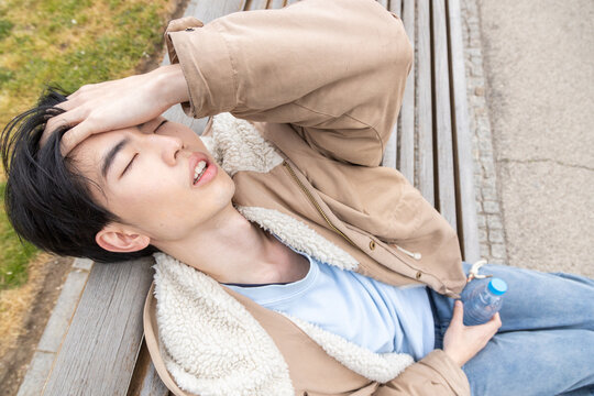 Young man experiencing headache and weakness outdoors
