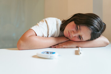 Young girl feeling tired due to hypoglycemia with glucose meter