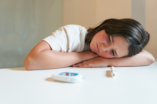 Young girl feeling tired due to hypoglycemia with glucose meter