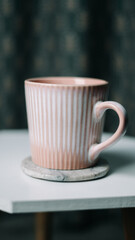 A striking image of a pink mug set against a dark background. The vibrant pink colour of the mug stands out dramatically, creating a bold contrast with the deep, shadowy backdrop. Ideal for highlighti