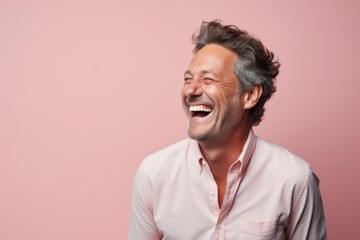 Obraz premium Portrait of a tender man in his 40s laughing in front of pastel or soft colors background