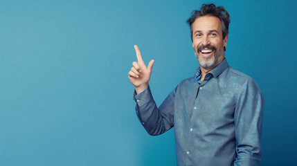 Confident Man in a Blue Blazer Smiling and Pointing to the Side with Enthusiasm, Set Against a Blue Background