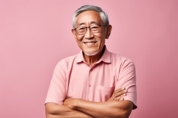 Obraz premium Portrait of a happy asian man in his 80s with arms crossed on pastel or soft colors background
