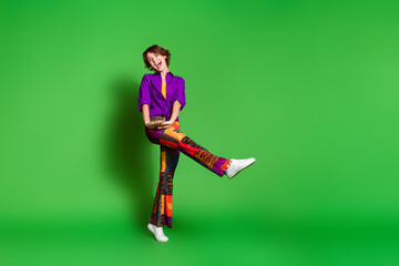 Photo of funny young woman in brand shirt vintage pants and brown bob haircut dancing near mockup isolated on green color background
