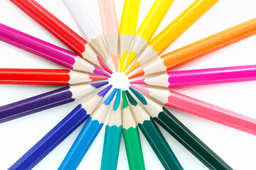 Colored pencils laid out in a circle on a white background