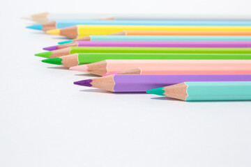 Pastel colored pencils in uneven row on a white background