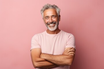 Portrait of a joyful man in his 60s with arms crossed in front of pastel or soft colors background