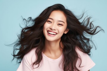 Naklejka premium Portrait of a jovial asian woman in her 20s smiling at the camera in pastel or soft colors background