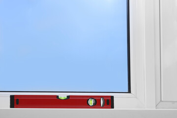 Red building level on white windowsill indoors, space for text