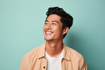 Obraz premium Portrait of a blissful asian man in his 20s smiling at the camera over pastel or soft colors background