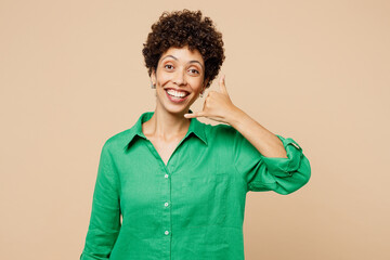 Young smiling woman of African American ethnicity wear green shirt casual clothes doing phone gesture like says call me back isolated on plain pastel light beige background studio. Lifestyle concept.
