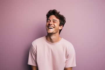 Obraz premium Portrait of a tender man in his 20s laughing in pastel or soft colors background