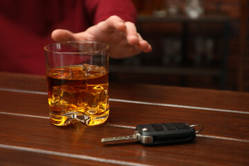 Man reaching for alcoholic drink at table with car keys, closeup. Don't drink and drive concept
