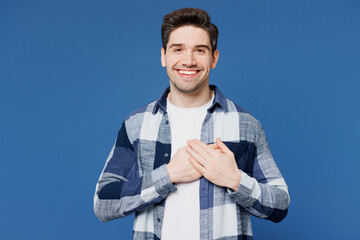 Fototapeta premium Young smiling grateful Caucasian man he wear shirt white t-shirt casual clothes put folded hands on heart look camera isolated on plain blue cyan color background studio portrait. Lifestyle concept.