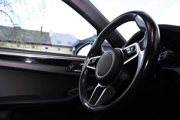 Steering wheel inside modern black car, closeup view