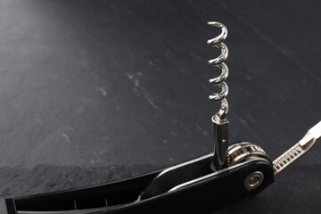 One corkscrew (sommelier knife) on grey textured table, closeup