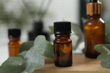 Aromatherapy. Bottles of essential oil and eucalyptus leaves on table