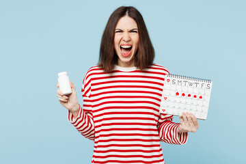 Young angry woman wear red casual clothes hold female periods pms calendar checking menstruation...