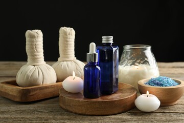 Spa composition. Cosmetic products, herbal bags, burning candles and sea salt on wooden table...
