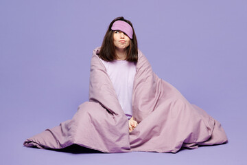 Full body young sad bored calm woman wear pyjamas jam sleep eye mask rest relax at home sit wrapped...
