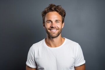 Obraz premium Portrait of a glad man in his 30s smiling at the camera in front of minimalist or empty room background