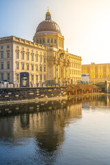 Fototapeta premium Golden morning sunlight bathes the Berlin Palace and Humboldt Forum, reflecting on the calm waters. Berlin, Germany