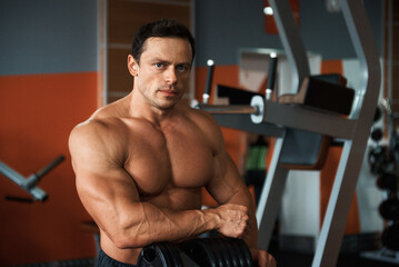 Bodybuilder posing for a magazine in the gym. Grain effect used