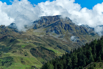 Scenic view of mountain panorama near village Andermatt in the Swiss Alps with cables of cable car...