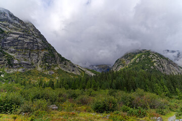 Alpine landscape in the Swiss Alps with fog and peak at mountain pass Grimsel on a cloudy autumn day. Photo taken September 19th, 2023, Grimsel, Canton Bern, Switzerland.